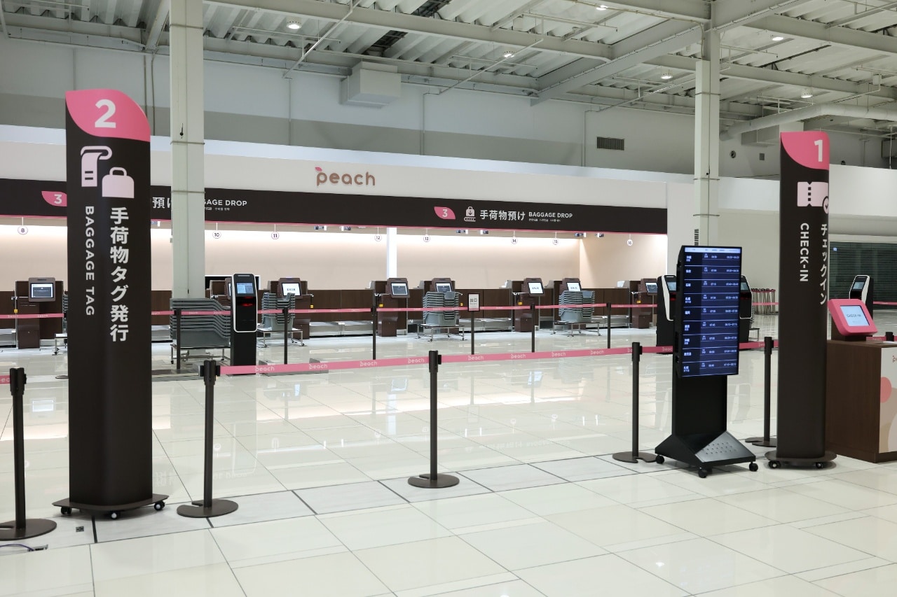 「チェックイン」や「手荷物タグ発行」の案内表示が設置されている空港ターミナルの写真