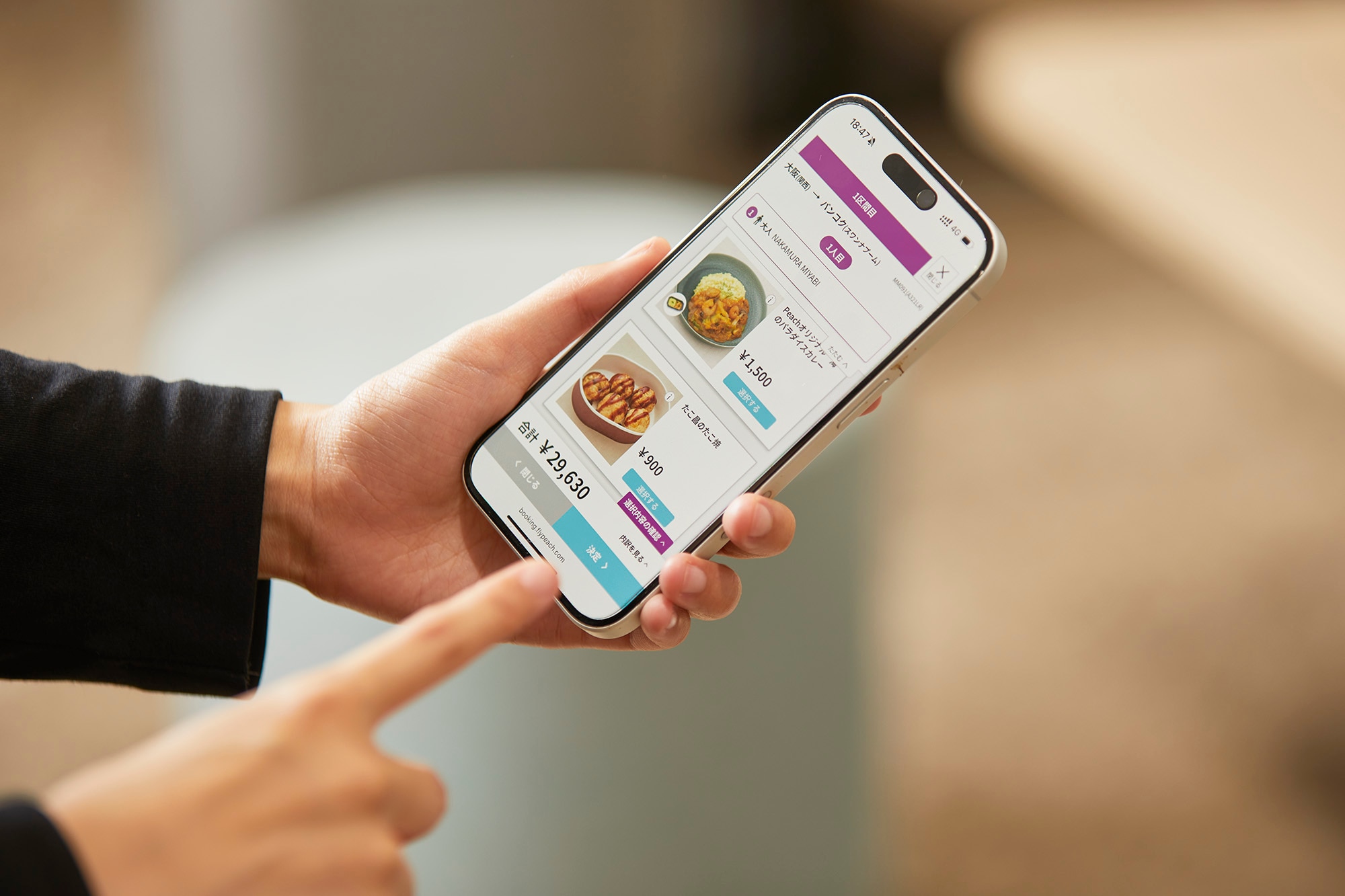 機内食の事前予約画面が表示されているスマートフォンを持つ手の写真