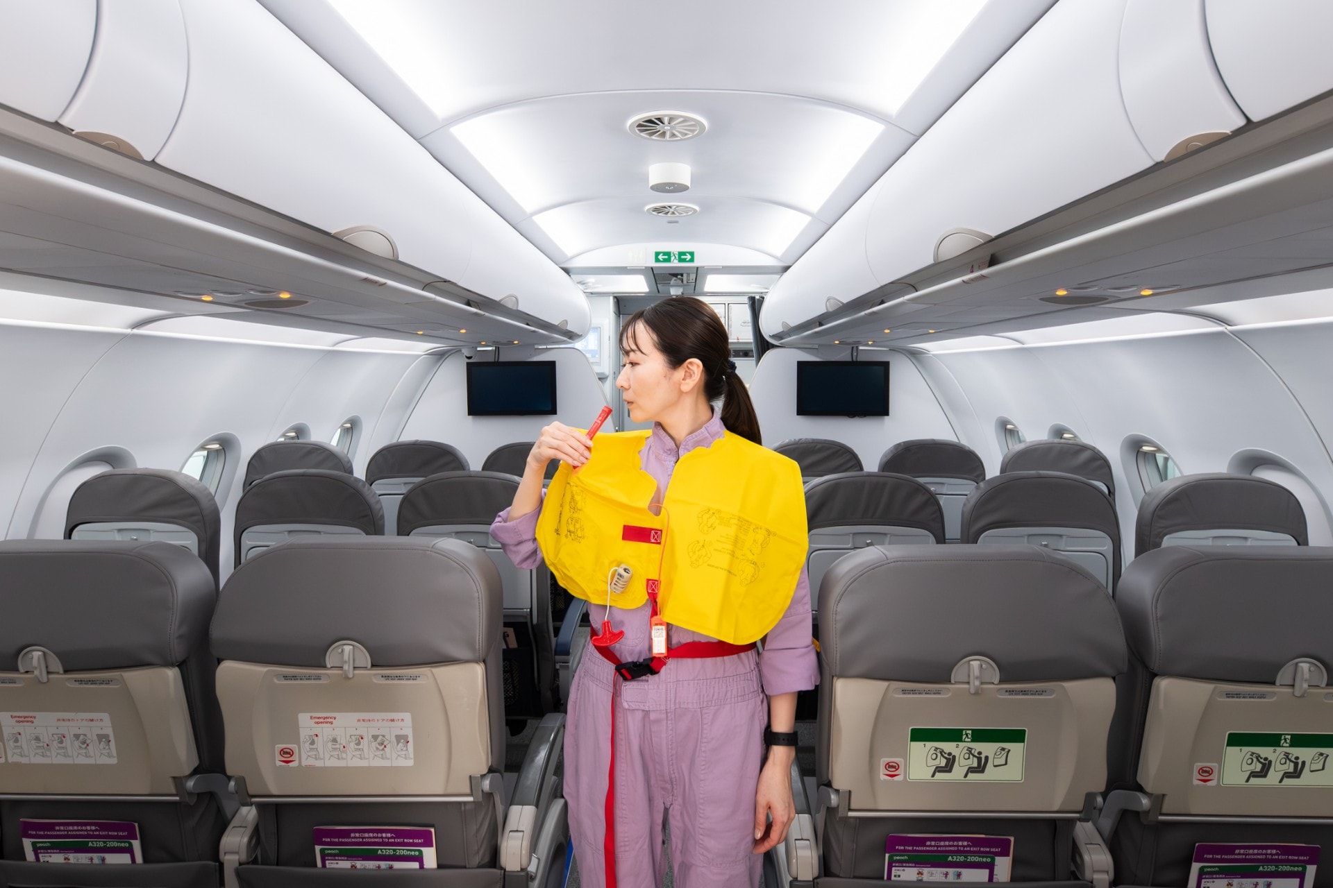 訓練用の機内で救命胴衣を膨らませているPeachのスタッフの写真